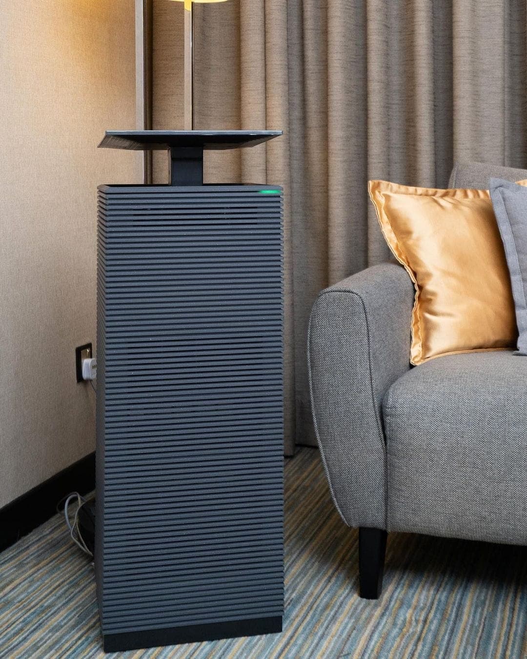 Coway Noble II air purifier standing beside a sofa in a living room